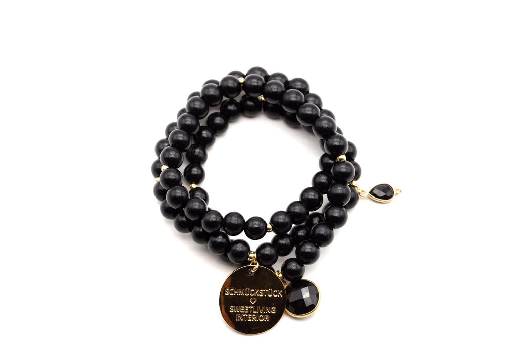 Dreifach gewickeltes Armband aus schwarzen Holzperlen mit vergoldetem Logo-Tag und facettiertem Onyx-Anhänger