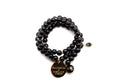 Dreifach gewickeltes Armband aus schwarzen Holzperlen mit vergoldetem Logo-Tag und facettiertem Onyx-Anhänger