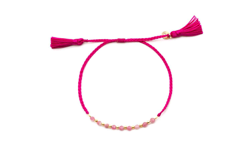Pink geflochtenes Macramé-Armband mit Turmalin-Perlen, vergoldeten Perlen und zwei Quasten, freigestellt