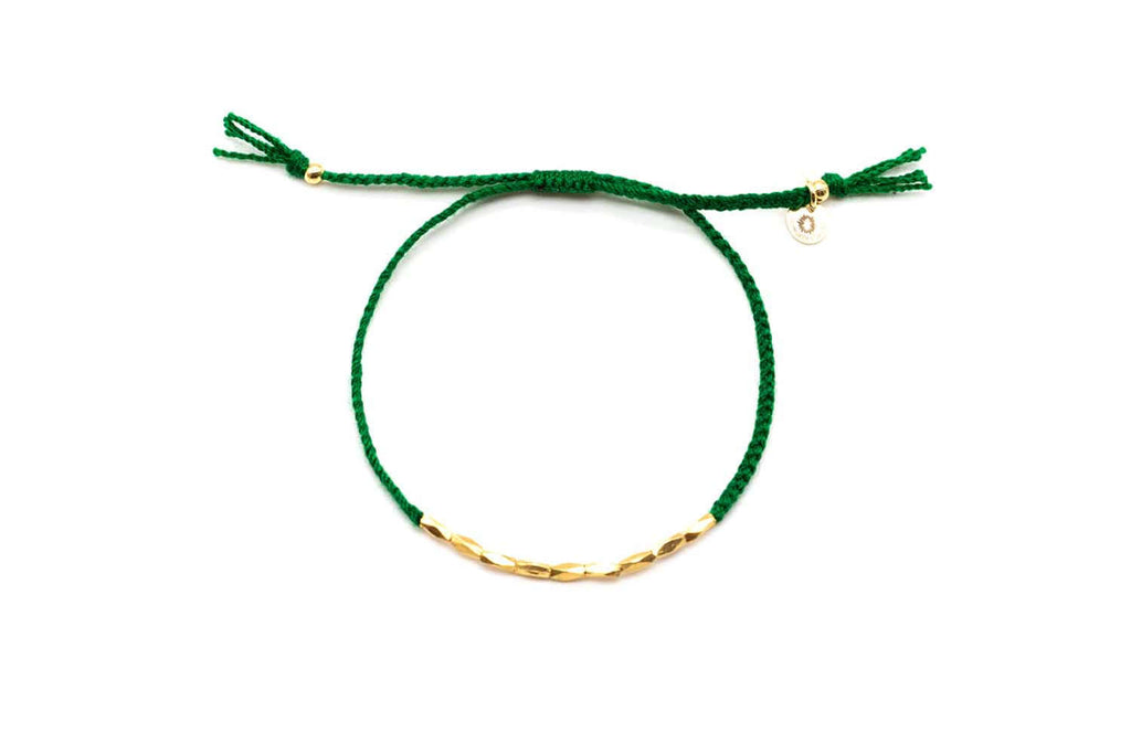 Grünes Macramé-Armband mit Reihe vergoldeter länglicher Perlen, freigestellt vor Weiß