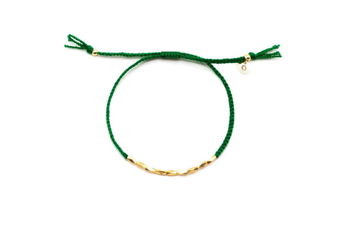 Grünes Macramé-Armband mit Reihe vergoldeter länglicher Perlen, freigestellt vor Weiß
