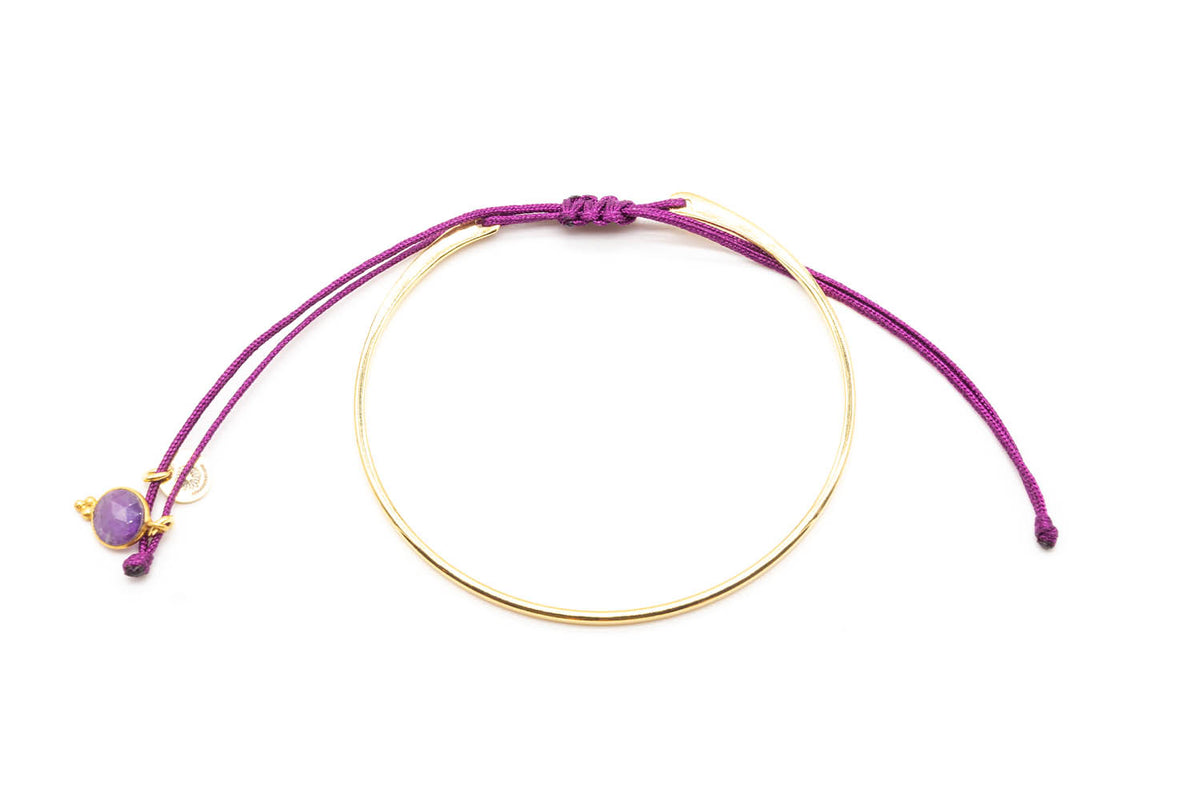 Vergoldeter Armreif mit lila geflochtenem Macramé-Band und Amethyst-Anhänger, freigestellt