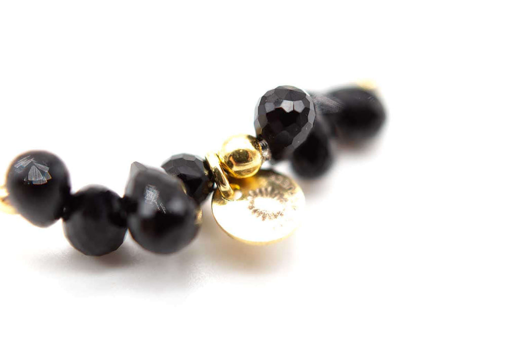 Detailaufnahme der schwarzen Onyxtropfen mit goldfarbenem Anhängerplättchen