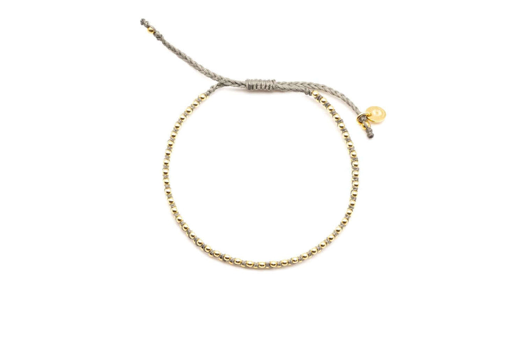 Armband auf grauem geflochtenem Macramé mit vergoldeten Perlen und Verschluss-Anhänger, freigestellt