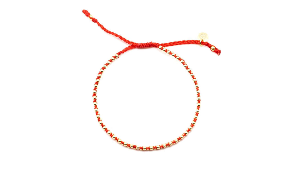 Geflochtenes Macramé-Armband in Rot mit vergoldeten Perlen und Zugverschluss, freigestellt vor hellem Hintergrund