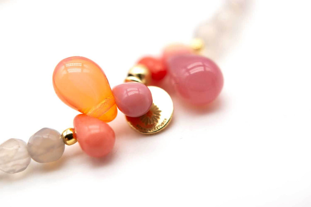 Nahaufnahme der rosa und orangefarbenen tropfenförmigen Perlen mit goldfarbenem Plättchen