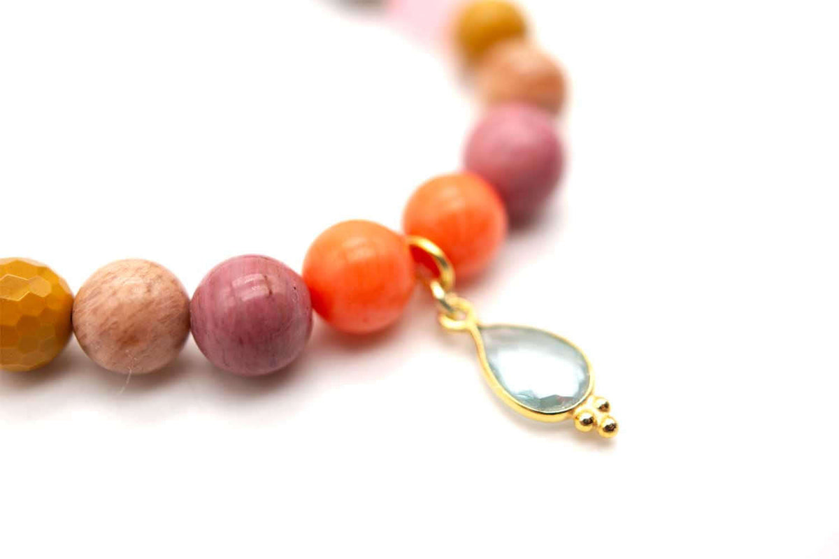 Detailaufnahme der orangefarbenen und rosa Perlen mit hängendem hellblauem Tropfen-Anhänger
