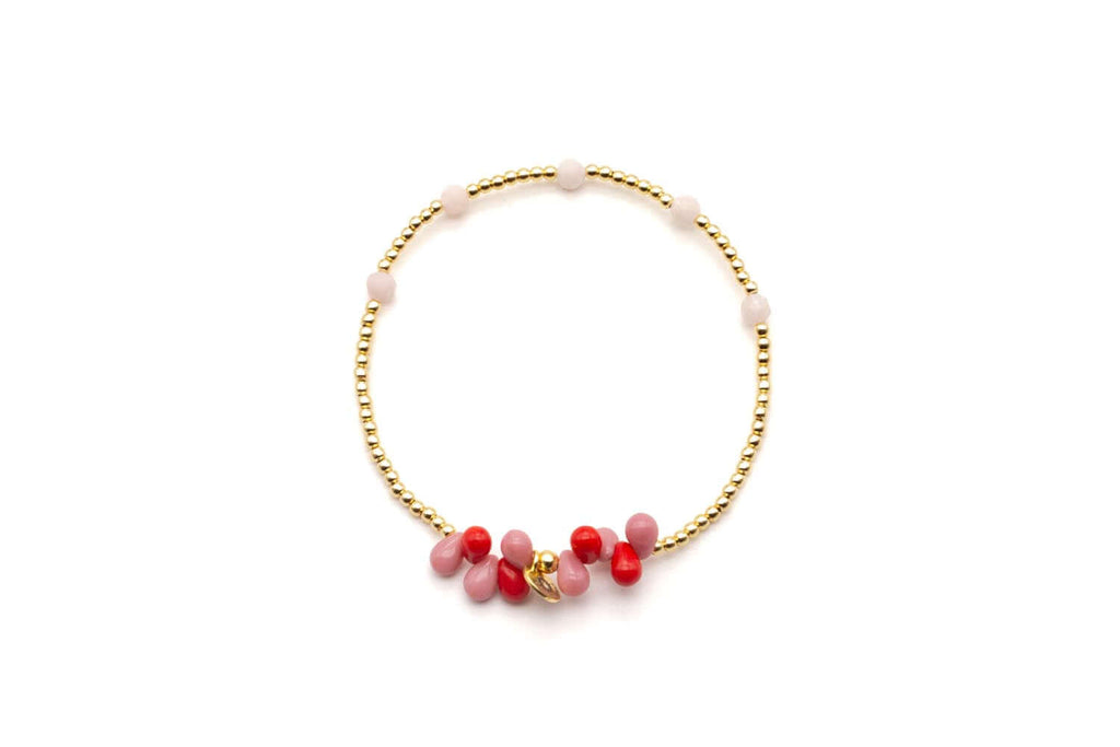 Armband auf Elastikband mit vergoldeten Perlen und tropfenförmigen Edelsteinen in Rosa und Rot, freigestellt