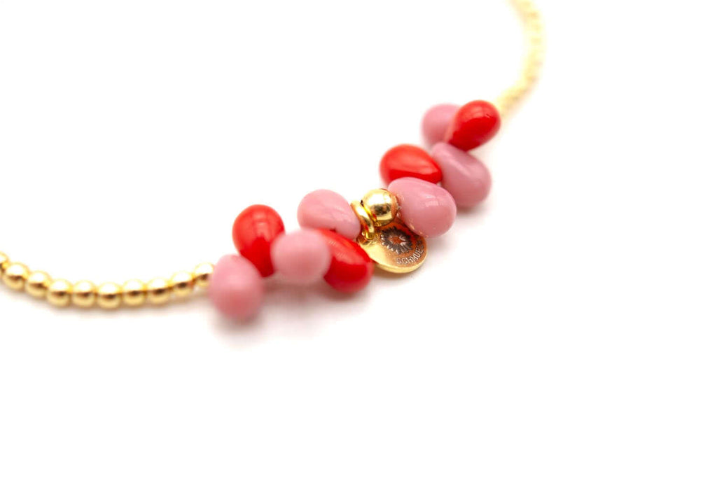 Detailaufnahme der rosa und roten Tropfenperlen mit kleinem goldfarbenem Anhänger