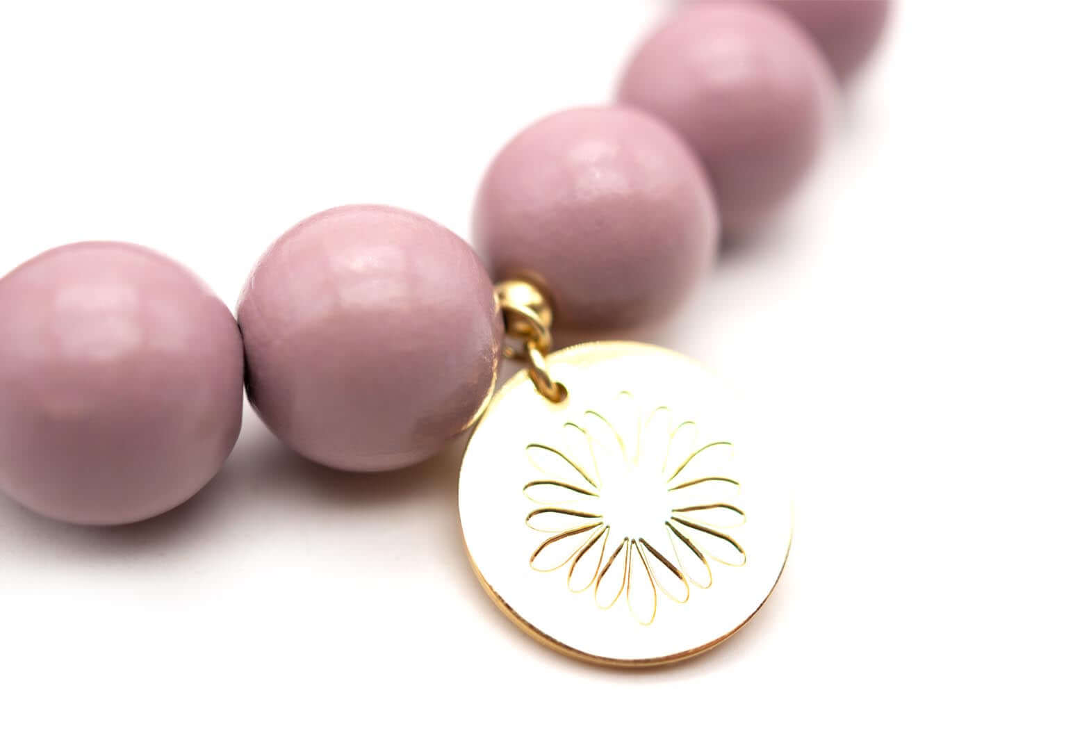 Detail des vergoldeten Logo-Tags mit ausgestanztem Blütenmuster