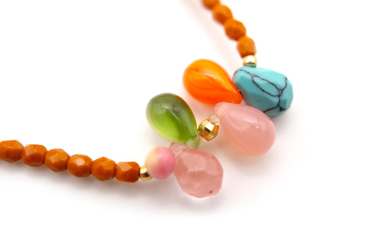 Detailaufnahme der bunten Kristalltropfen in Orange, Grün, Rosa und Türkis mit goldfarbenen Perlen