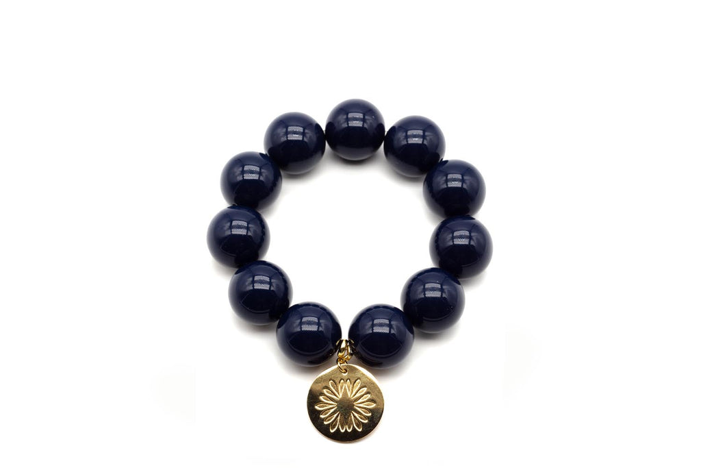 Armband auf Elastikband mit großen dunkelblauen Acrylperlen und vergoldetem Anhänger mit Blütenmotiv