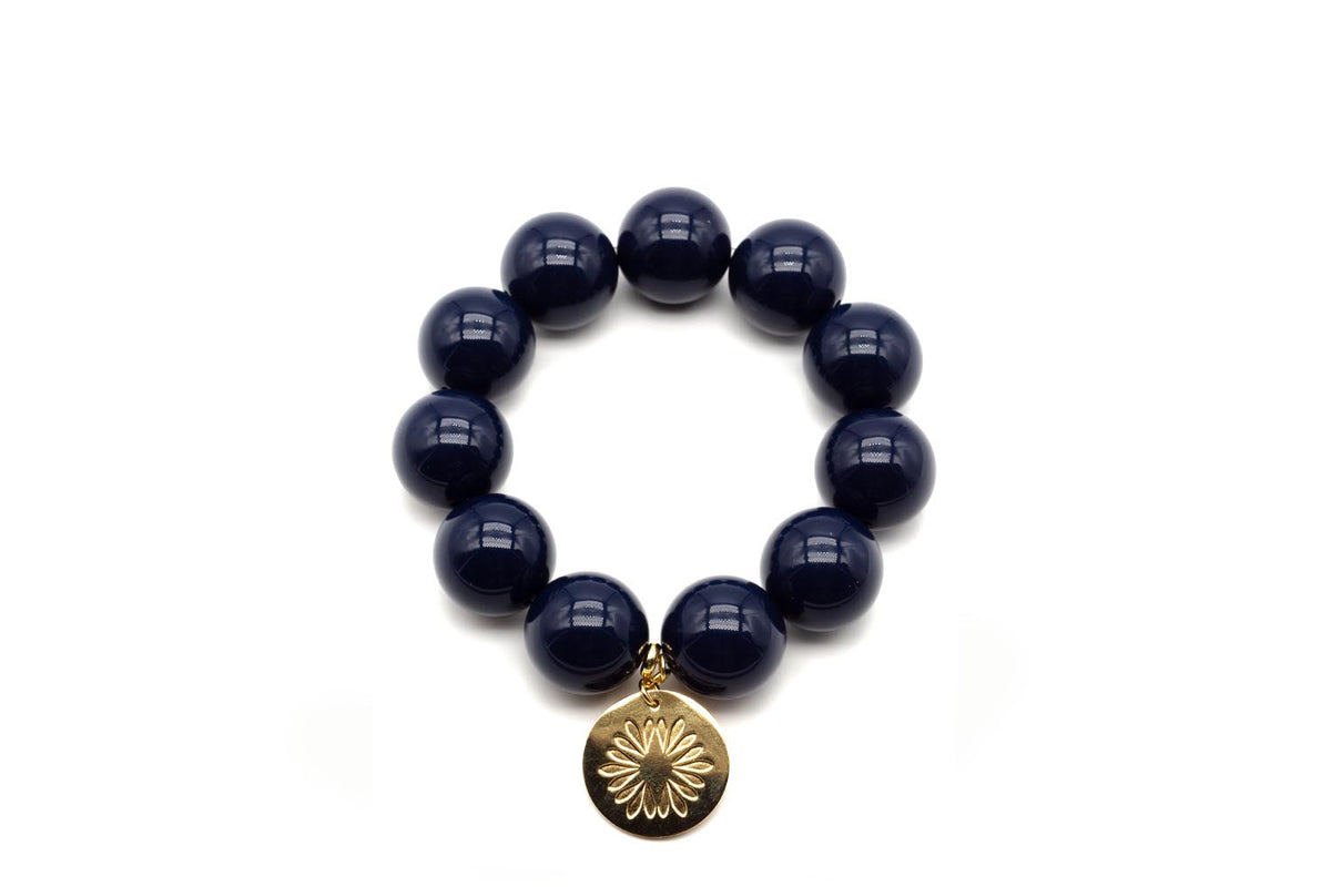 Armband auf Elastikband mit großen dunkelblauen Acrylperlen und vergoldetem Anhänger mit Blütenmotiv