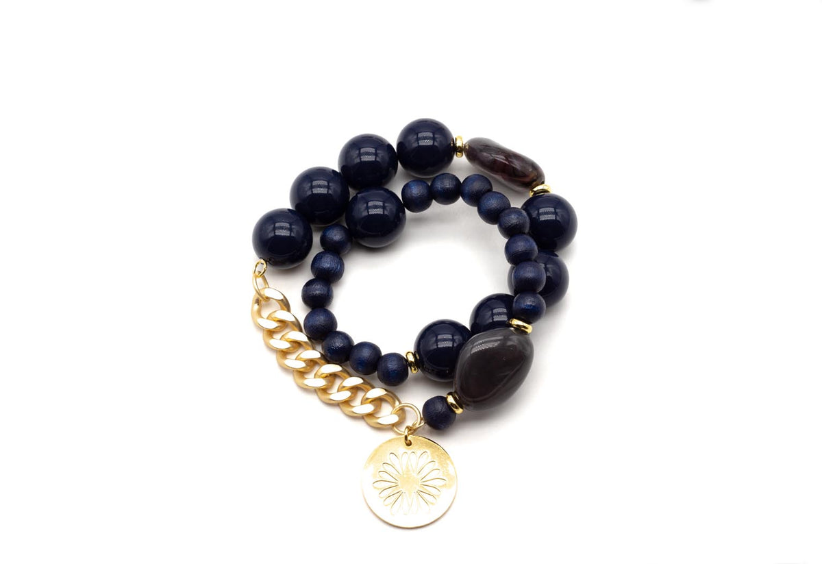 Doppeltes Armband auf Elastikband mit dunkelblauen Perlen, goldfarbenem Gliedanhänger und rundem Logo-Tag
