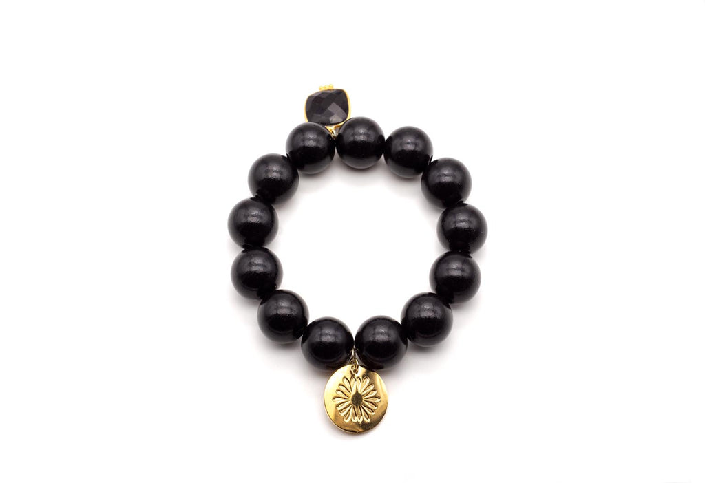 Armband auf Elastikband mit schwarzen Holzperlen, facettiertem Onyx-Anhänger und vergoldetem Logo-Tag
