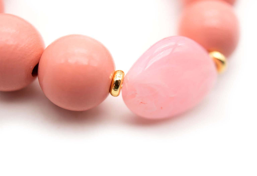Detailaufnahme des rosa Acrylsteins zwischen Holzperlen mit vergoldeten Zwischenperlen