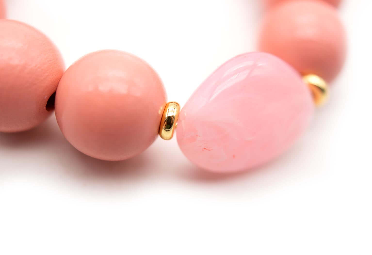Detailaufnahme des rosa Acrylsteins zwischen Holzperlen mit vergoldeten Zwischenperlen