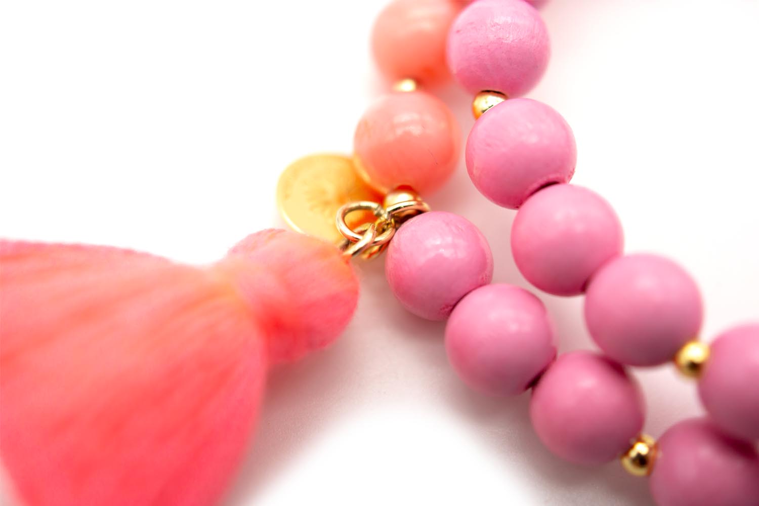 Detail der korallenfarbenen Quaste mit goldfarbenem Plättchen und rosa Perlen
