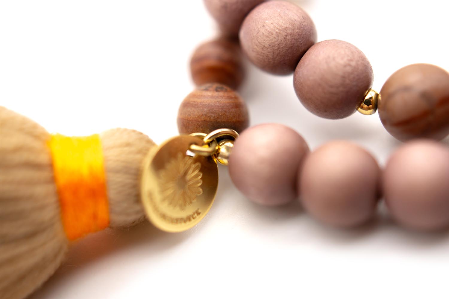 Detail von Quaste mit orangefarbener Wicklung, vergoldetem Plättchen und Holzperlen