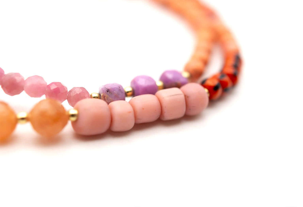 Detailaufnahme der beiden Perlenstränge mit rosa, lila und orangefarbenen Perlen