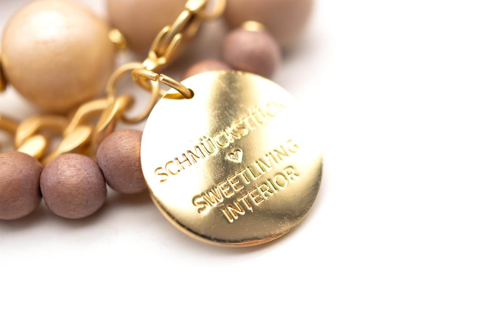 Nahaufnahme des vergoldeten runden Logo-Anhängers mit Gravur Schmückstück Sweetliving Interior