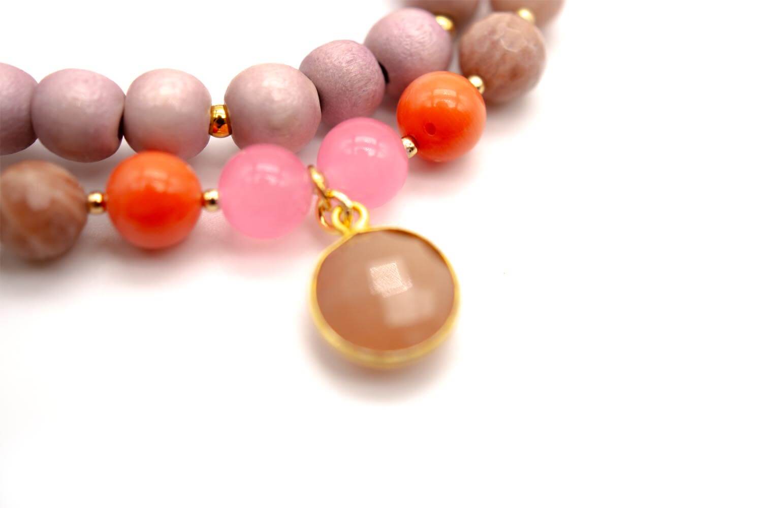 Nahaufnahme der orange und rosa Perlen mit facettiertem Rosenquarz-Anhänger in vergoldeter Fassung
