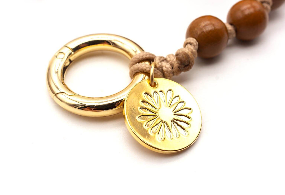 Nahaufnahme der vergoldeten Logo-Münze mit Blütenmotiv am goldfarbenen Ring