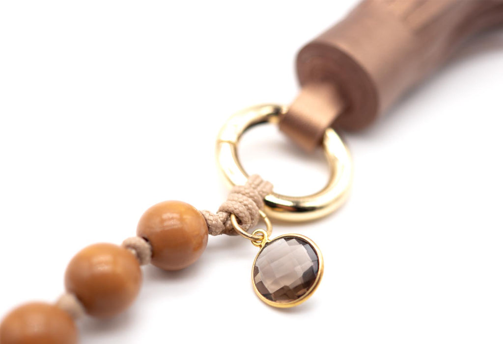 Detailansicht des goldfarbenen Rings mit facettiertem Rauchquarz-Anhänger und Lederquaste