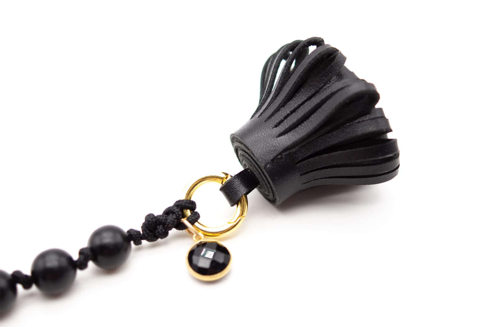 Detailaufnahme der Nappaleder-Quaste mit facettiertem Onyx-Anhänger am goldfarbenen Ring