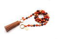Lange Handykette aus geflochtenem Nylon mit braun-orangefarbenen Holzperlen, brauner Lederquaste und Karneol-Anhänger
