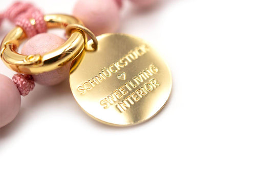 Nahaufnahme des runden, vergoldeten Logo-Tags am Karabinerring