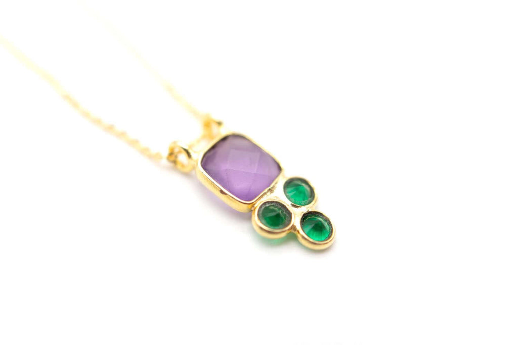 Detailaufnahme des Anhängers mit facettiertem Amethyst und drei glänzenden grünen Steinen