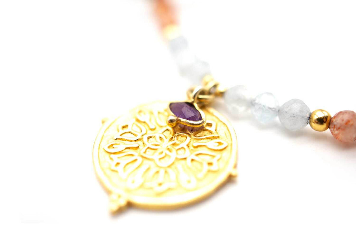Detailaufnahme des ornamentierten Münzanhängers mit violettem Edelstein