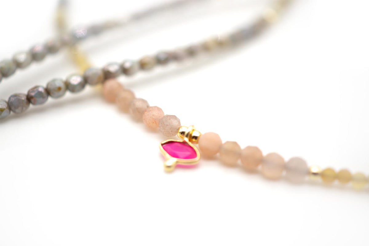 Detailaufnahme des pinkfarbenen Chalcedon-Anhängers zwischen rosa und grauen Perlen
