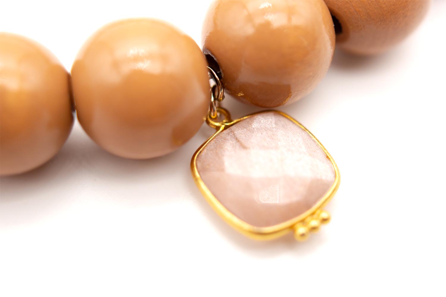 Detailaufnahme des quadratischen, rosé schimmernden Edelstein-Anhängers in goldfarbener Fassung