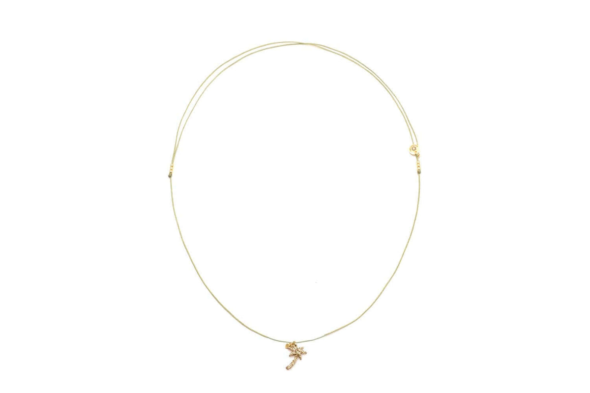 Choker aus grüner Nylonschnur mit goldfarbenem Palmen-Anhänger, freigestellt vor Weiß
