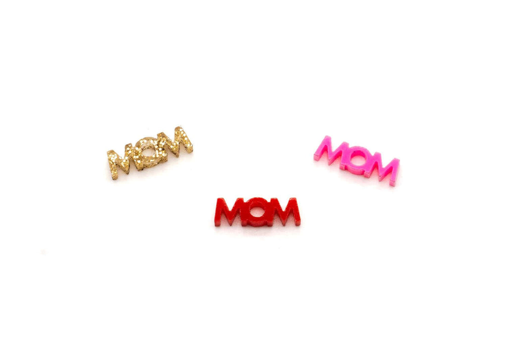 Drei Mom-Schriftzug-Anhänger aus Acryl in goldfarbenem Glitzer, Rot und Pink freigestellt