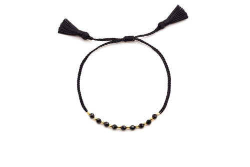 Geflochtenes schwarzes Armband mit facettierten Onyx-Perlen, vergoldeten Zwischenperlen und zwei Quasten