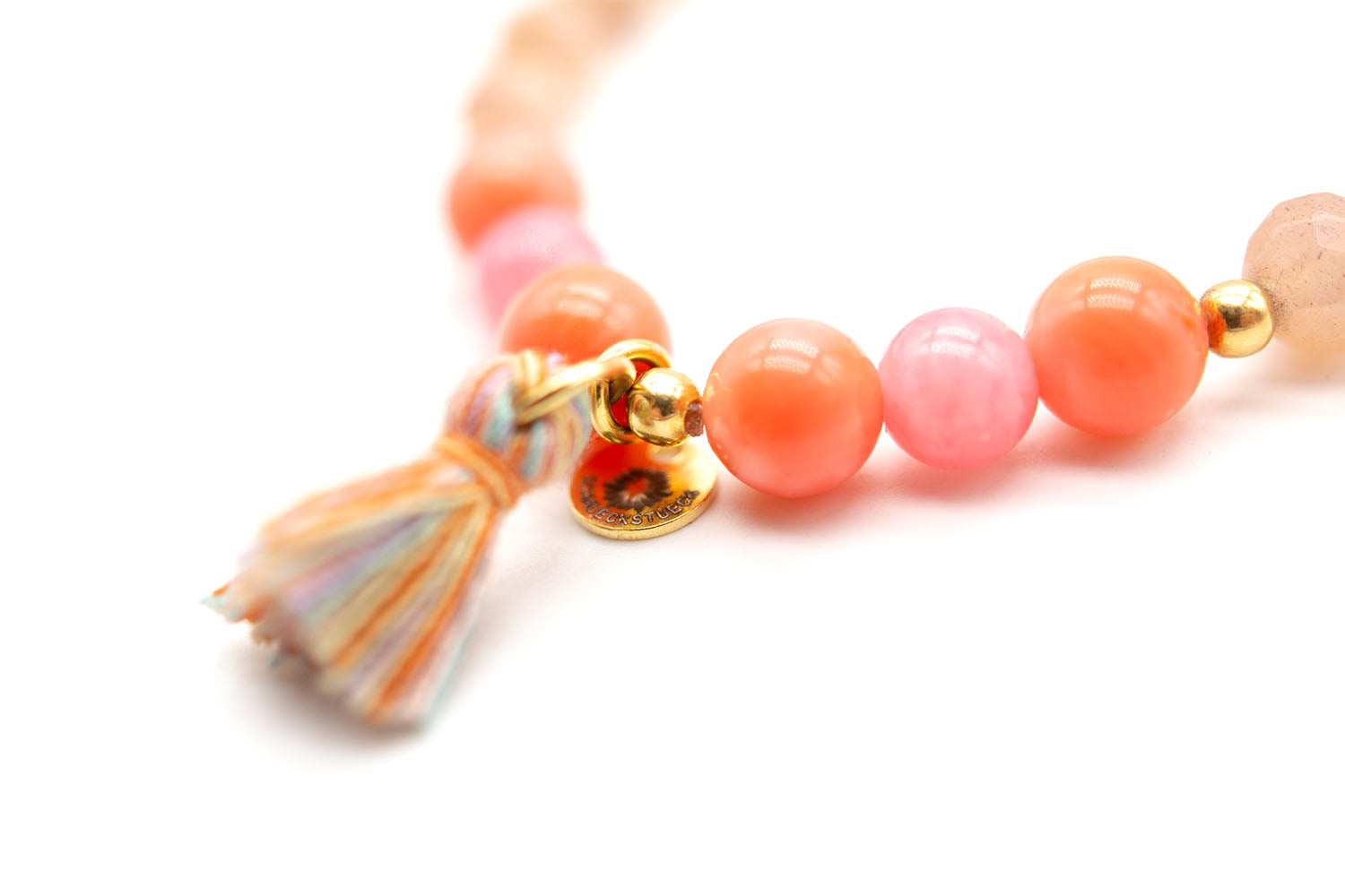 Nahaufnahme der orange-rosa Korallenperlen mit heller Quaste