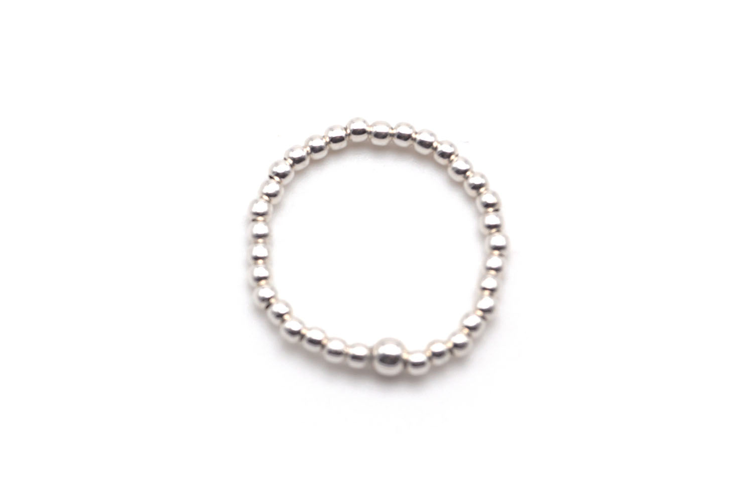 Ring aus kleinen Sterlingsilber-Perlen auf Elastikband, freigestellt vor hellem Hintergrund